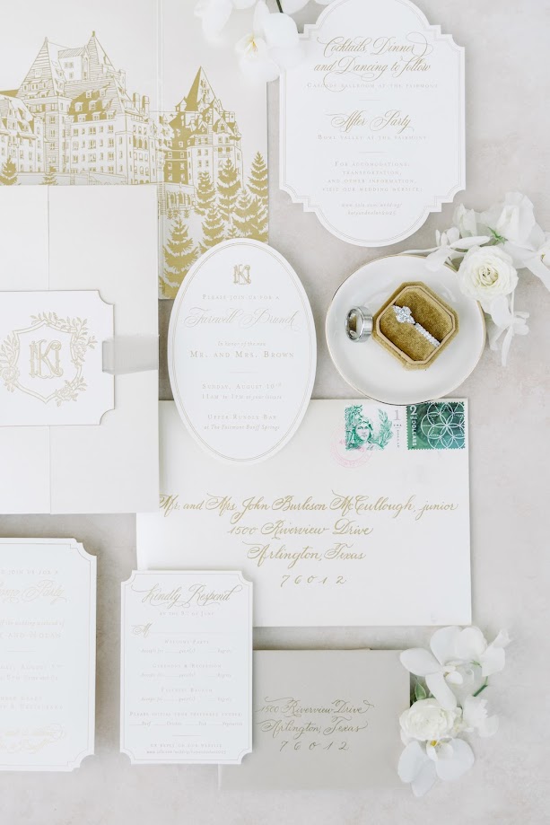 An all white invitation suite with gold accents, gold foil, featuring a drawing of the wedding venue - Fairmont Banff Springs
